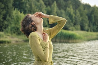 Bright sunlight illuminates the lush surroundings as a woman enjoys a hot day by the lake, laughing