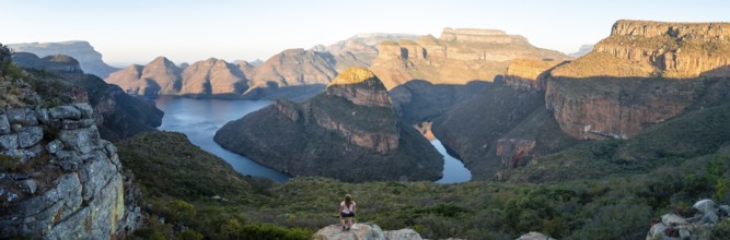 Hiker enjoying panorama, sunset at Blyde River Canyon with Three Rondawels peak, view of canyon