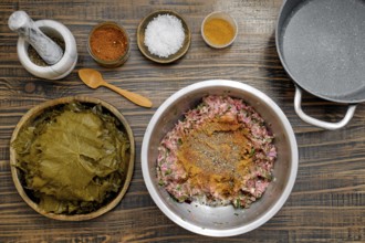 Preparing dolma involves mixing ground meat with spices and herbs on a rustic kitchen table. Fresh