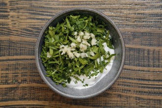Freshly chopped herbs, including parsley and garlic, are mixed with creamy yogurt in a rustic
