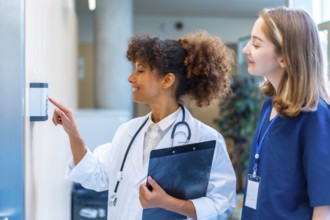 Female doctor entering security pin code on keypad access control, next to a nurse, in a hospital