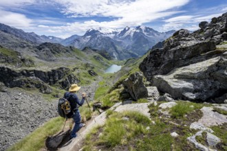 Mountaineer on hiking trail in mountain landscape, descent at Col du Louvie, view of mountain lake