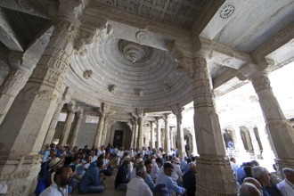 Indian men praying between the white marble pillars in the Adinath temple in Ranakpur, Jain temple,