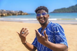 Young man enjoying summer vacation on a tropical beach, smiling widely and gesturing joyfully while