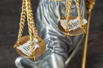 Symbolic image: Close-up of the scales of Justitia with two torn-off leaves labelled LEFT and RIGHT