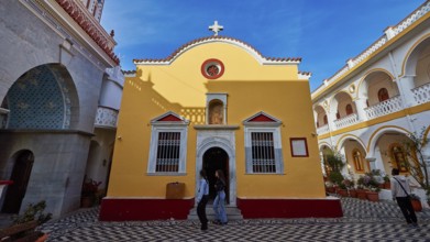 Yellow baroque-style church with cross and floor pattern in the courtyard, Holy Week, Panormitis