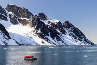 Zodiac in front of mountains with snow, sea, Smeerenburg, Spitsbergen, Svalbard
