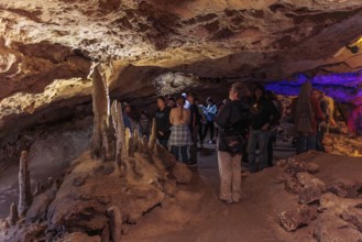 Tourists walking past limestone rock formations in a cave at Florida Caverns State Park in the