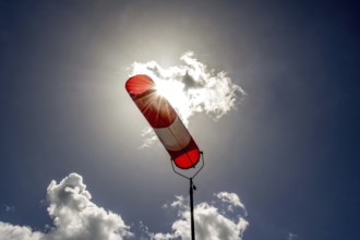 A colorful windsock hangs from a tall pole, clearly indicating wind direction. The bright sky is