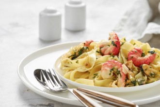 A plate of fettuccine allo Scoglio features fresh pasta topped with shrimp, mussels, and herbs,