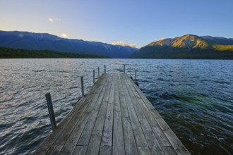 Wooden walkway stretches across the lake with mountains at sunrise, summer, Lake Rotoiti, Saint