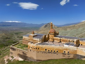 Historic fortress in Turkey, surrounded by green landscape and mountains, under a blue sky, aerial
