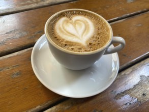 Cup of cappuccino, flat white, with heart-shaped milk foam, wooden table, Stuttgart,