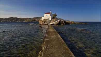 White chapel with red roof on a small island, connected to the mainland by a footbridge, chapel,