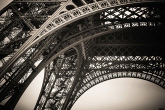 Beneath the iconic Eiffel Tower, the stunning architectural design is highlighted against a gray