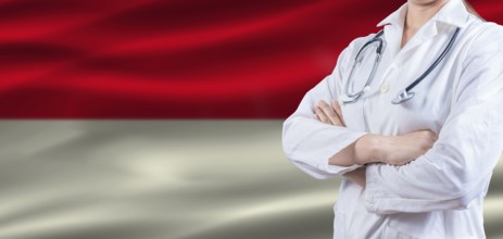 Doctor with crossed arms on Indonesia flag. Indonesia health and care concept. Female doctor on
