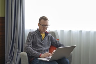 A middle-aged man sits comfortably in an armchair and watching as real estate agent showing a