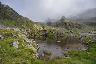 Small mountain lake, cloudy mountain peaks reflected in the lake, Schober group, Hohe Tauern
