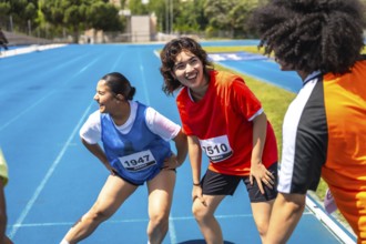 Runners stretching their legs on a vibrant blue track, recovering after a race, embodying teamwork