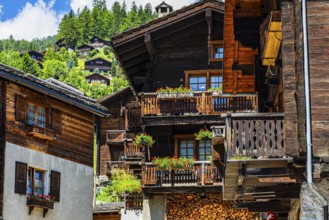 Old wooden houses in log construction, decorated with flowers, historic village centre, Grimentz,