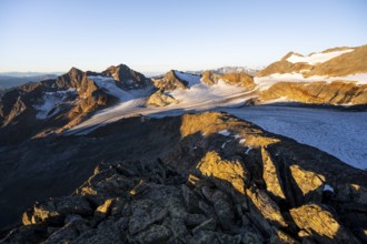 Picturesque high mountain landscape at sunrise with alpenglow, glacier and rocky mountain peaks in