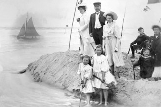 Family on the beach, 1910s, Victorian beach shot of a family with children next to a sailing boat
