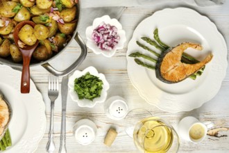 A beautifully arranged meal featuring a salmon fillet on asparagus, accompanied by seasoned
