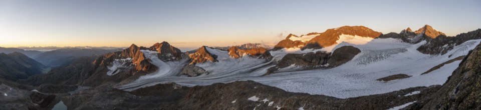 Picturesque high mountain landscape at sunrise with alpenglow, glacier and rocky mountain peaks in