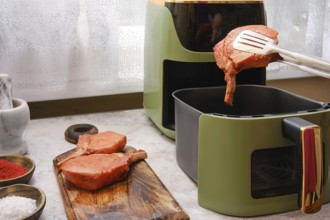 Thick pork rib chops are being cooked in an air fryer, showcasing the ease of preparing tender meat