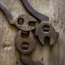 Three vintage hand tools, including adjustable wrenches, rest on a rustic wooden workbench. The