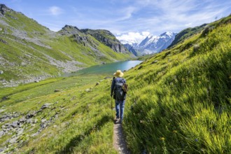 Mountaineer on hiking trail in picturesque mountain landscape, view of mountain lake Lac du Louvie