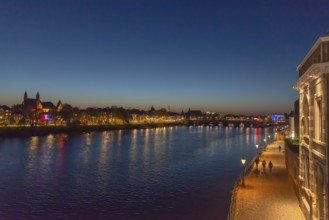 Maastricht, Netherlands, night view of the river Maas with illuminated bridge and promenade, under