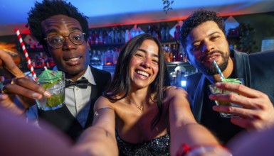 Cheerful multi ethnic friends enjoying cocktails and capturing joyful selfies at a vibrant
