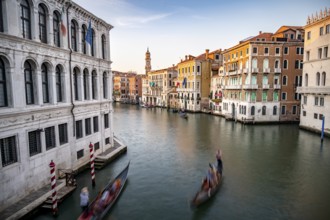View of the Grand Canal with gondoliers at sunset, picturesque evening mood with palazzos on the
