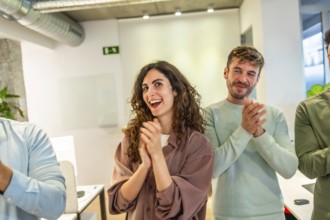 Group of smiling businesspeople applauding during a meeting in a modern office, celebrating success