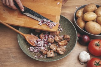 Adding chopped onion to the pan with meat, close-up