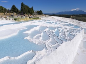 View of limestone terraces with turquoise blue water surrounded by trees and tourists, aerial view,