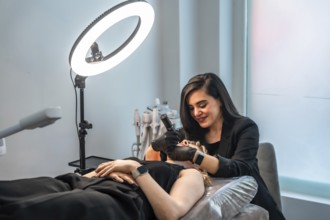 Professional beautician performing a facial treatment using a led light therapy device on a client