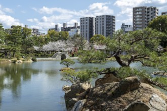 Shukkei-en with Sekisui-gan stone formation, green plants, trees and Koko-kyo stone bridge over