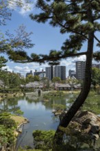 Shukkei-en with Sekisui-gan stone formation, green plants, trees and Koko-kyo stone bridge over