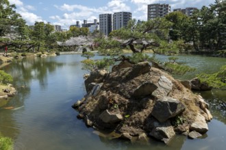 Shukkei-en with Sekisui-gan stone formation, green plants, trees and Koko-kyo stone bridge over
