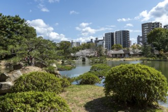 Shukkei-en with green plants and Takuei-chi pond in spring, historical Japanese strolling garden,