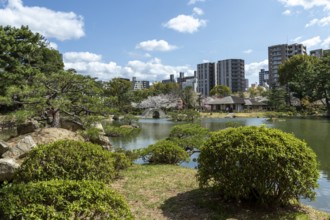 Shukkei-en with green plants and Takuei-chi pond in spring, historical Japanese strolling garden,