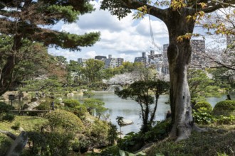 Shukkei-en with green plants, trees and Takuei-chi pond in spring, historical Japanese strolling