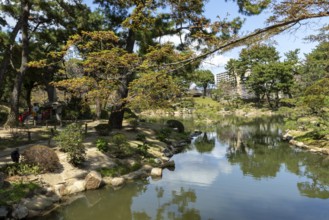 Shukkei-en with green plants, trees and Takuei-chi pond in spring, historical Japanese strolling