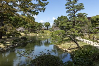 Shukkei-en with green plants, trees and Takuei-chi pond in spring, historical Japanese strolling