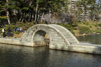 Shukkei-en with Koko-kyo stone bridge over Takuei-chi pond in spring, historical Japanese strolling