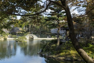 Shukkei-en with Koko-kyo stone bridge over Takuei-chi pond in spring, historical Japanese strolling
