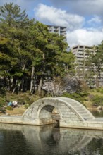 Shukkei-en with Koko-kyo stone bridge over Takuei-chi pond in spring, historical Japanese strolling