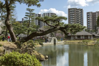 Shukkei-en with Seifukan teahouse and Koko-kyo stone bridge over Takuei-chi pond in spring,
